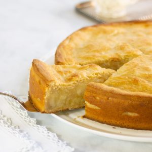 Deep apple pie with one slice cut on a silver serving knife