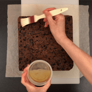 Basting and feeding square fruit cake with brandy