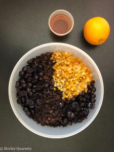 Dried fruit in a tub with some rum and an orange